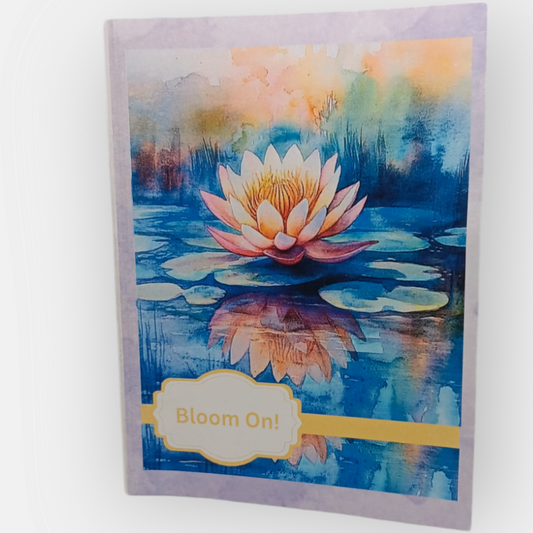 Note card with a light purple background and a watercolor image of a blooming lotus mirrored on still water, with the message “Bloom On” on the cover.
Image Description: A  note card featuring a blooming lotus on a light purple background, with the words “Bloom On” on the cover. The inside is blank.